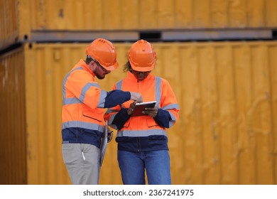 Male and Female engineers with orange safety jackets working at train station  - Shutterstock ID 2367241975