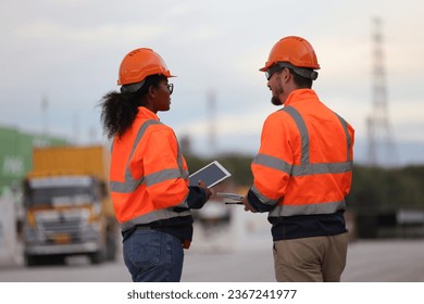 Male and Female engineers with orange safety jackets working at train station  - Shutterstock ID 2367241977