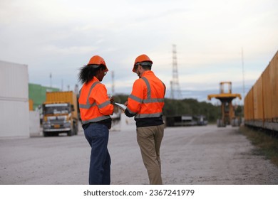Male and Female engineers with orange safety jackets working at train station  - Shutterstock ID 2367241979