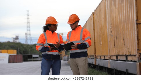 Male and Female engineers with orange safety jackets working at train station  - Shutterstock ID 2367241981