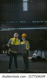 Male And Female Engineers Spreading The Floor Plan Inside The Factory And Discussing To Plan The Installation Of New Types Of Machines