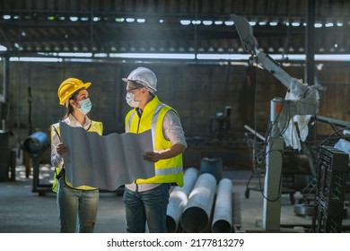 Male And Female Engineers Spreading The Floor Plan Inside The Factory And Discussing To Plan The Installation Of New Types Of Machines