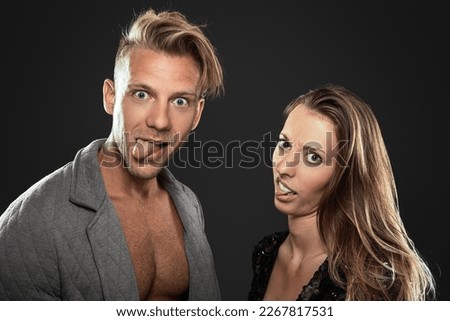 male and female friends fool around as couple doing silly grimace at camera with tongue out and big eyes