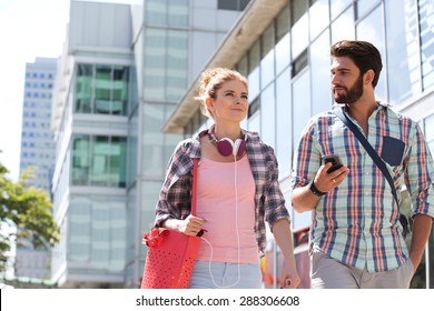 Male And Female Friends Walking Outside Office Building On Sunny Day