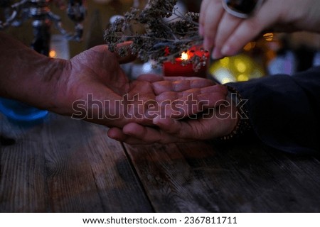 male, female hands close-up, session of magic in dark room of fortuneteller, magic items on table, Chiromancy Fortune Telling, palm divination for future, activity at halloween party