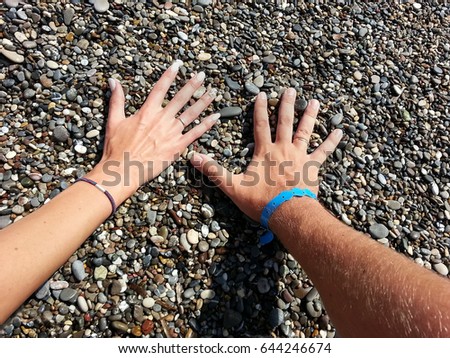 Male and female hands on a background of wet pebbles