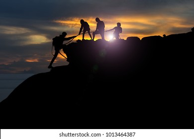 Male And Female Hikers Climbing Up Silhouette Mountain Cliff . Teamwork ,success ,helps , Business Concept. 