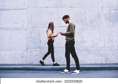 Male and female hipsters walking on grey wall background ignoring each other preferring social networks,students chatting online instead of communicating in real life strolling pon publicity area - Powered by Shutterstock