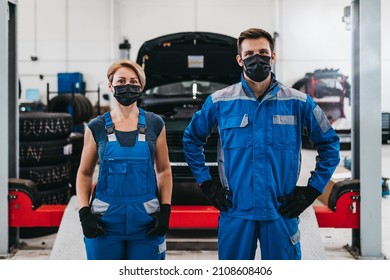 Male and female mechanics with protective face masks are working together in large modern car repair service. - Powered by Shutterstock