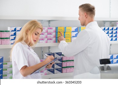 Male And Female Pharmacists Checking Inventory At Pharmacy