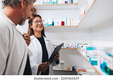 Male and female pharmacists working together in a chemist. Two mature healthcare professionals doing an inventory take in a pharmacy.