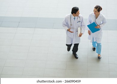 Male And Female Physicians Talking While Walking In The Hospital, View From Above