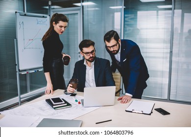 Male And Female Professional Entrepreneurs Analyzing Information From Website On Laptop Computer During Collaboration.Group Of Skilled Employees Watching Training Webinar In Web Page On Gadget