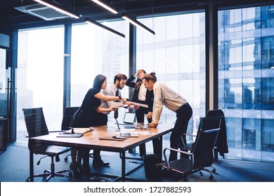 Male and female professionals teamworking during brainstorming cooperation on paper documents, group of diverse employers discussing corporate investment of firm capital briefing in conference room