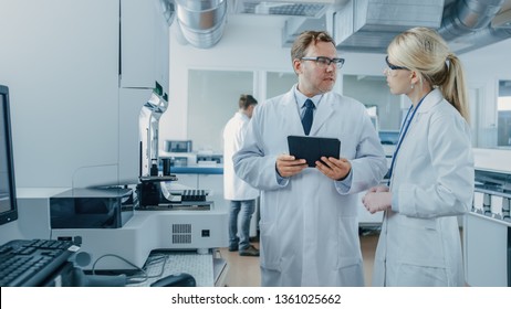 Male and Female Research Scientists Talking, Using Digital Tablet Computer while Working on Genetics Research Project in Innovative Laboratory.