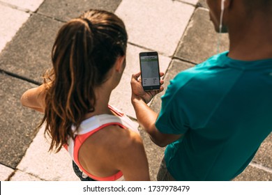 Male And Female Runner Using A Fitness App On Mobile Phone. Fitness People Checking The Summary Of Their Run On Smartphone.