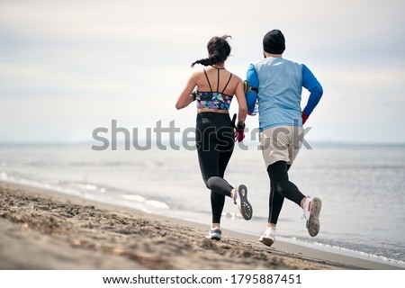 Male and female runner workingout on the beach