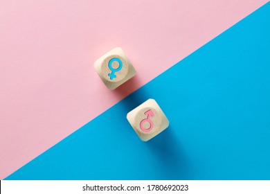 Male And Female Sex Icons On Wooden Cubes On Pink And Blue Background. Sex Change, Gender Reassignment, Transgender And Sexual Identity Concept.