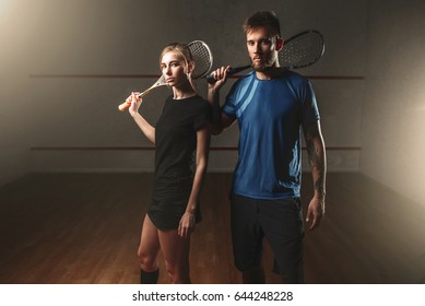 Male and female squash game players with rackets