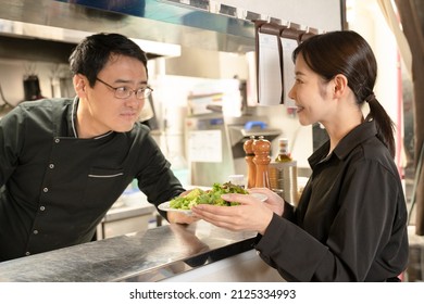 Male And Female Staff Serving Food At The Restaurant