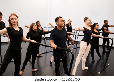 Male And Female Students At Performing Arts School Rehearsing Ballet In Dance Studio Using Barre