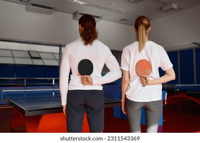 Male and female table tennis player holding racket behind back - Powered by Shutterstock