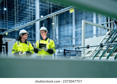 male and female technician engineers checking the process on Heavy machine. mechanical engineering team production. Industry manufacturing. Worker holding tablet and folde. High technology production. - Powered by Shutterstock