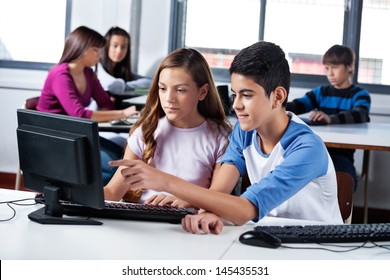 Male and female teenage friends using computer in lab