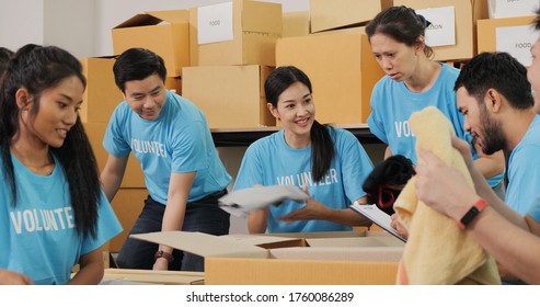 Male And Female Volunteer Preparing Clothes For Poor People During Covid19. As Charity Workers And Members Of The Community Work Together.