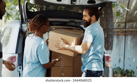 Male and female volunteers at the car giving charity boxes to poor needy and homeless people at community center. At food drive, the less privileged receive donations from a non-profit organization. - Powered by Shutterstock