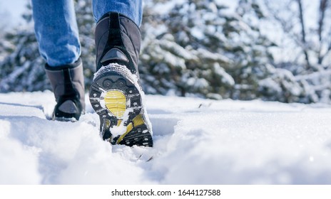 Male or female winter boots walking on snowy sleet road	