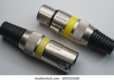 Male and female XLR jacks without cable, metallic material with yellow strips, isolated on white background, closeup macro shots