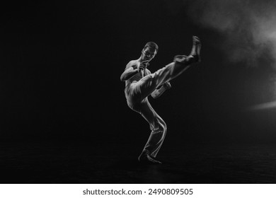 Male fighter training capoeira on black background - Powered by Shutterstock