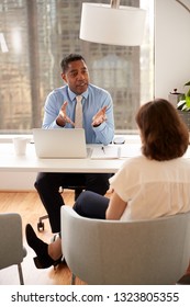 Male Financial Advisor In Modern Office Sitting At Desk Meeting Female Client