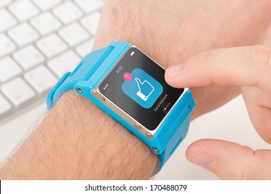 Male finger taps like icon on blue smart watch - Powered by Shutterstock