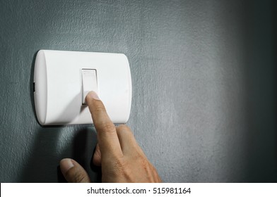 Male Finger Turn On Or Off White Lighting Switch On Rough Dark Grey Wall. Copy Space.