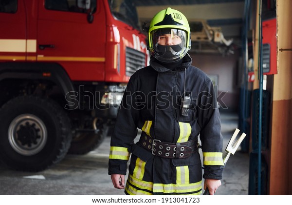 Male firefighter in protective uniform standing\
near truck.