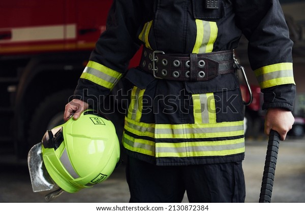 Male firefighter in protective uniform standing\
near truck.