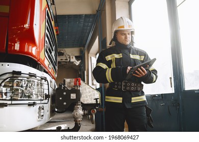 Male firefighter with tablet in uniform on car background - Shutterstock ID 1968069427