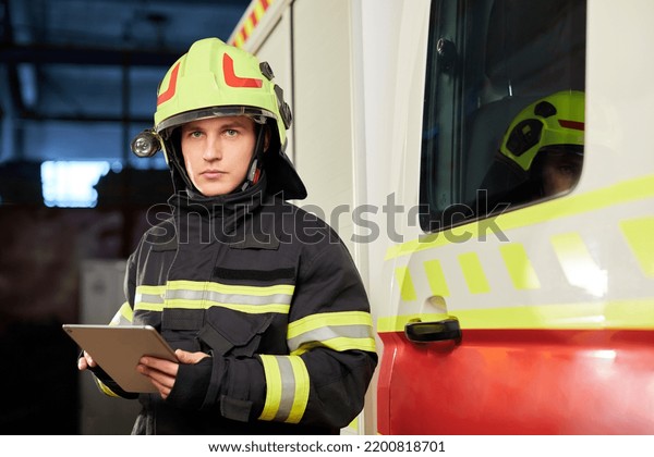 Male\
firefighter with tablet in uniform on car\
background