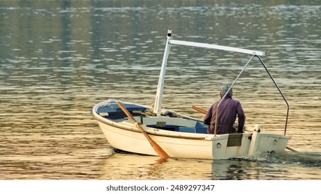 A male fisherman in a small boat peacefully floating down a river - Powered by Shutterstock