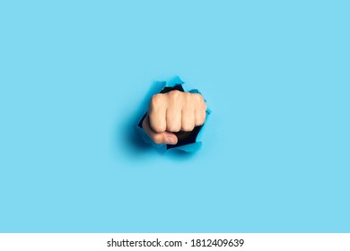 Male Fist Punches A Wall On A Blue Background. Banner. Breakout Gesture, Break