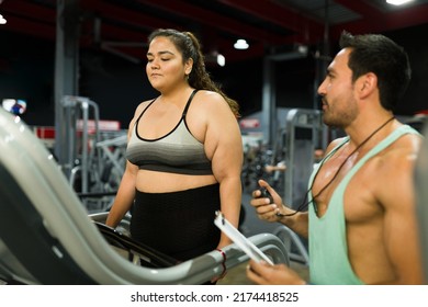 Male Fitness Coach Talking To A Plus Size Woman In A Treadmill About Her Cardio Workout And Diet Plan At The Gym