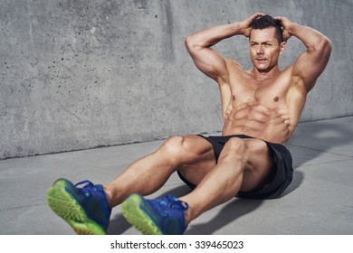 Male Fitness Model Doing Sit Ups And Crunches Exercising Abdominal Muscles, Six Pack Visible Wearing No Shirt