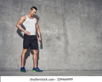 Male Fitness Model In White Tank Top Relaxing After Workout. Grey Background With Room For Text, Copy Space