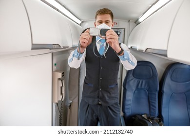 Male Flight Attendant Demonstrating How To Use Safety Belt In Aircraft