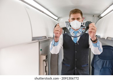 Male Flight Attendant In Medical Mask Holding Seatbelt