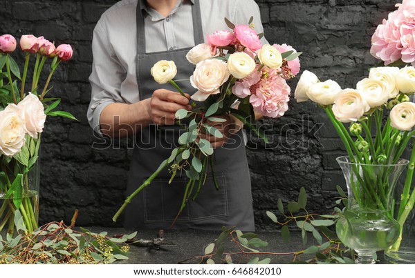 Male florist creating beautiful bouquet in flower\
shop, close up