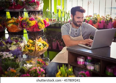 Male Florist Using Laptop At His Flower Shop