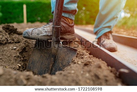 Male foot wearing a rubber boot digging an earth in the garden with an old spade close up. Soil preparing for planting in spring. Agriculture and people concept 